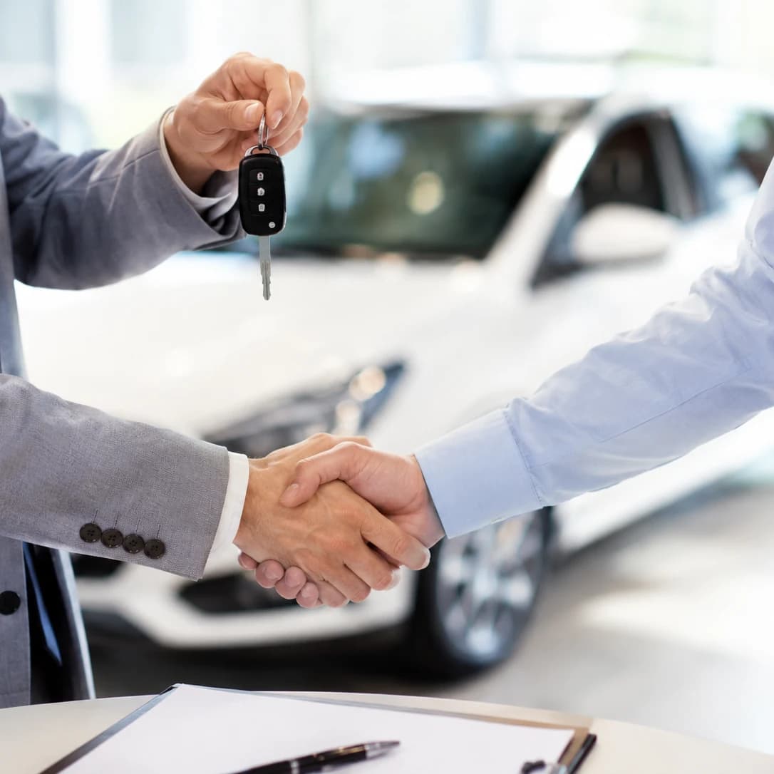 Sleuteloverdracht — handdruk tussen EK Cars verkoper en klant na succesvolle aankoop